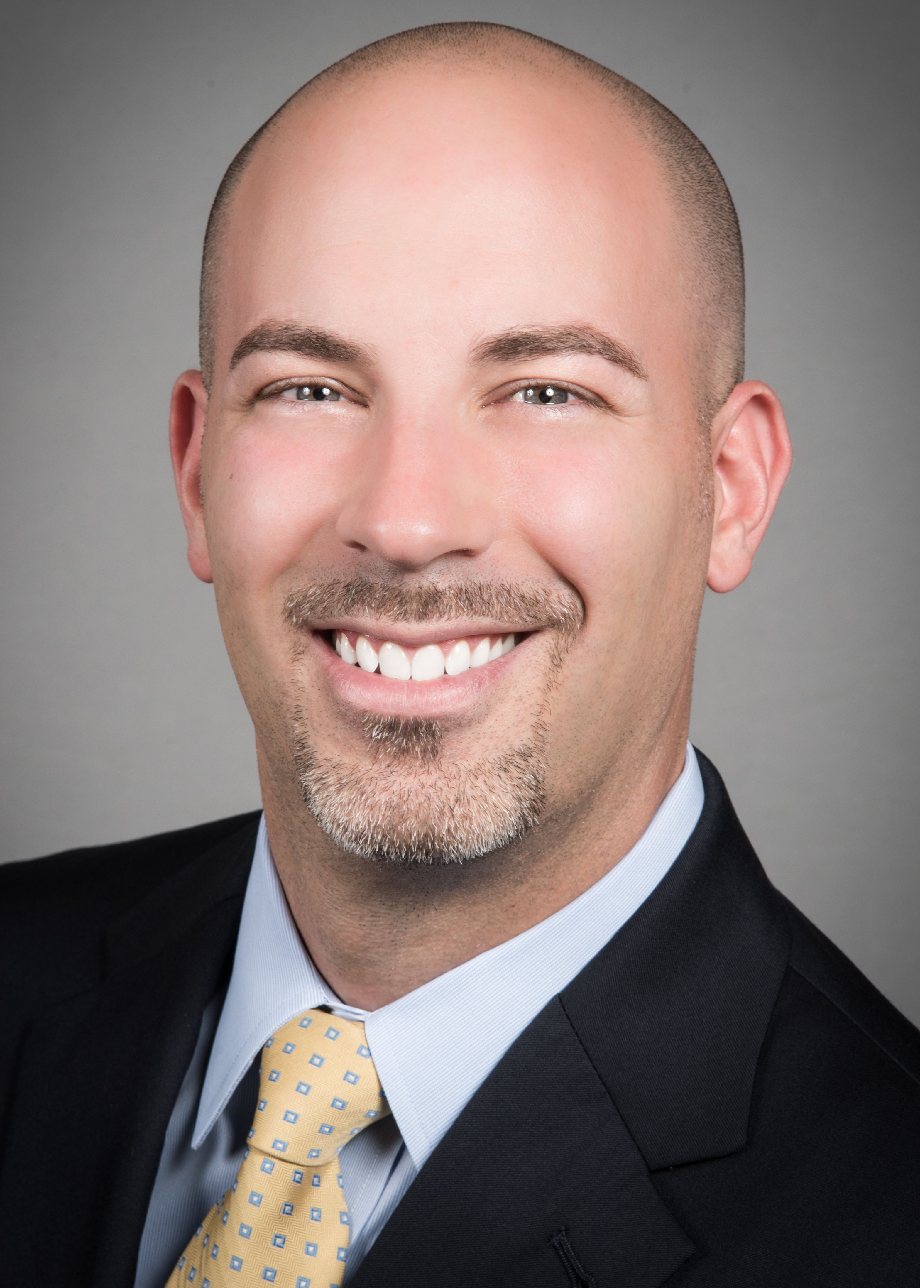 Michael Scarpelli in a black suit, blue shirt and yellow tie